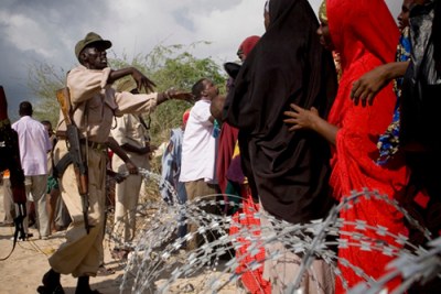 A soldier from Somalia's transitional government pushes back a crowd that awaits much needed medical treatment.