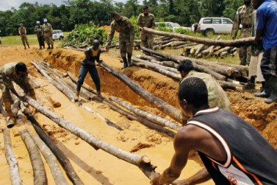 Pakistani UN peacekeepers and Liberian villagers repair a flooded road.