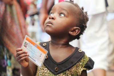Une petite fille tenant une carte d’électeur