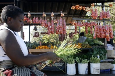 A woman sells vegetables at a food market in Harare