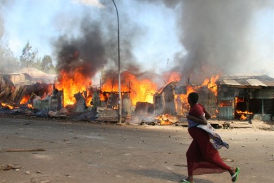 A pregnant woman runs past burning shacks in Nairobi's Mathare slum during 2007 post-election violence (file photo).