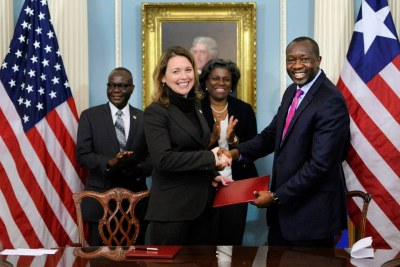 MCC CEO Dana J. Hyde, center, shakes hands with Liberian Minister of Finance and Development Amara M. Konneh (file photo).