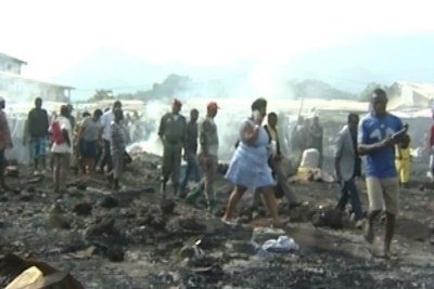 People assess the damage in part of a burned down market in Limbe
