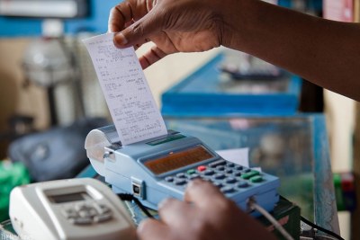A trader pulls out a sales receipt from an electronic billing machine.