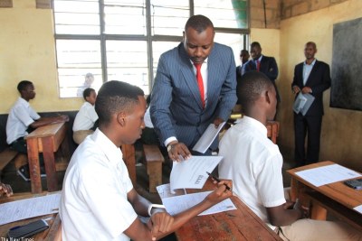 State Minister for Primary and Secondary Education, Isaac Munyakazi, distributes examination papers at GS Remera examination centre in Kigali Tuesday morning.