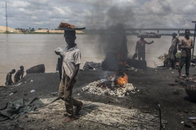 Children in Yenagoa, Bayelsa State, Nigeria pass in front of a flame fed by waste and rubber materials in order to make Kanda, a type of smoked meat, at an abattoir on October 24, 2016. The workers at the slaughterhouse use cow bones, rubber tyres, electric wires, aluminum cans and other waste to sustain the flames, making the fumes very dangerous to inhale.