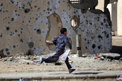 Un garçon passe devant des bâtiments endommagés, défigurés par les bombardements pendant le conflit, dans la ville de Syrte, en Libye.